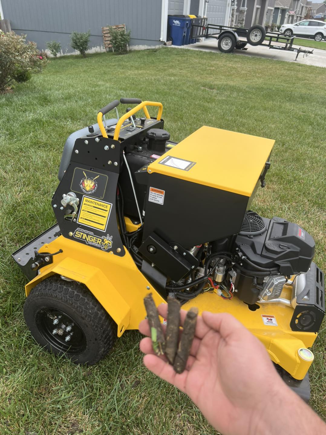 A crew member holding soil cores pulled during core aeration, next to the aerator.