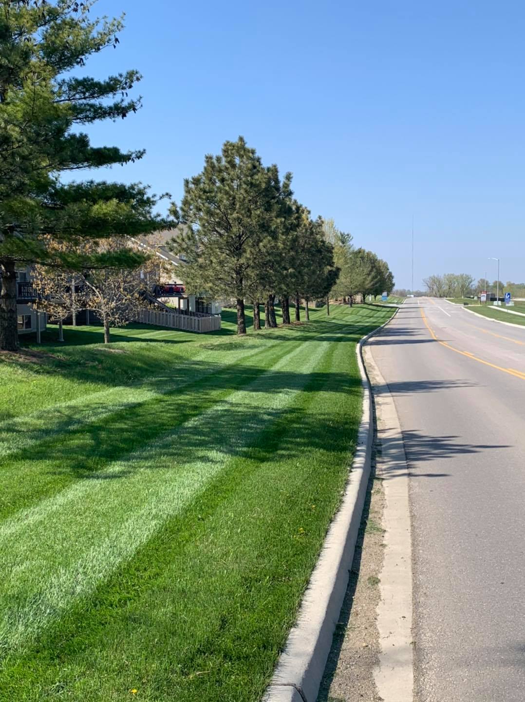 A commercial property frontage mowed in clean stripes along a main road.
